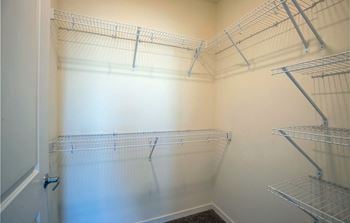 A spacious closet with shelves and empty shelves in a room with white walls